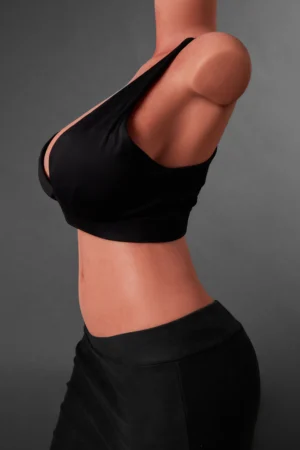 silicone torso sex doll featuring auburn hair and a black sports bra outfit in a studio setting