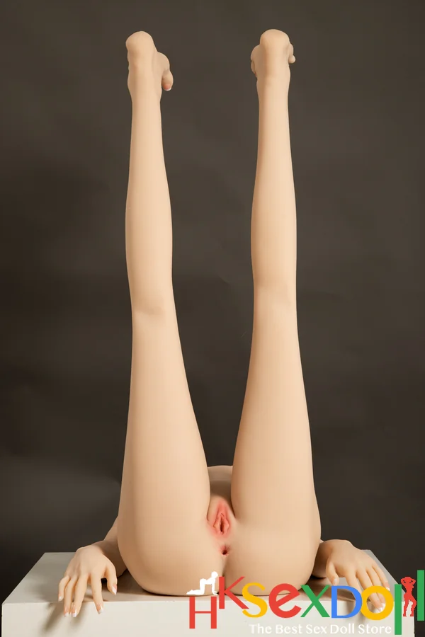 japanese petite sex doll with short brown hair sits playfully on a white shelf